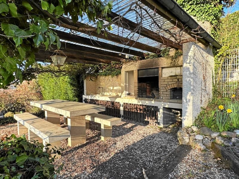 outdoor brick oven, wooden table, wooden benches, metal roof, hanging plants