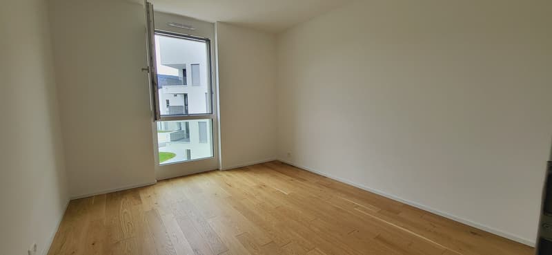 Spacious bedroom with hardwood flooring, large window providing natural light, and access to a balcony or terrace