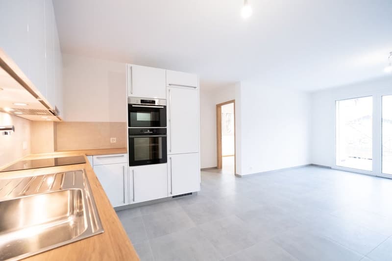 modern kitchen with integrated appliances, wooden countertop, white cabinets, tiled floor