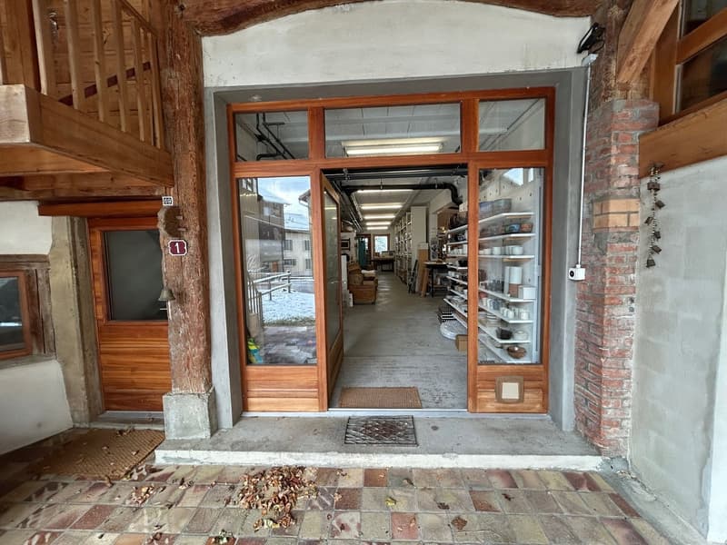 Wooden entrance, tiled walkway, storefront glass doors, interior shelves with items