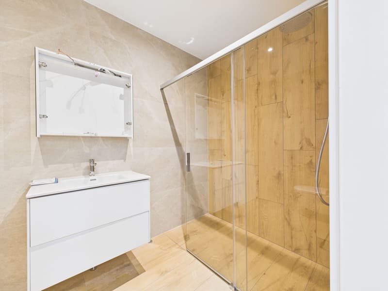Bathroom with walk-in shower, wooden tiles, white cabinets, tiled wall