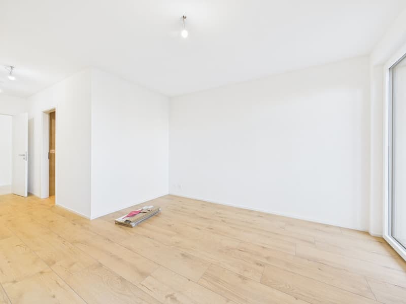 Empty room with hardwood floors, white walls, doors, and sliding glass door.