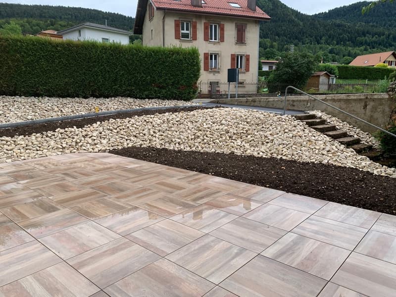A tiled walkway in a garden with gravel and plants.