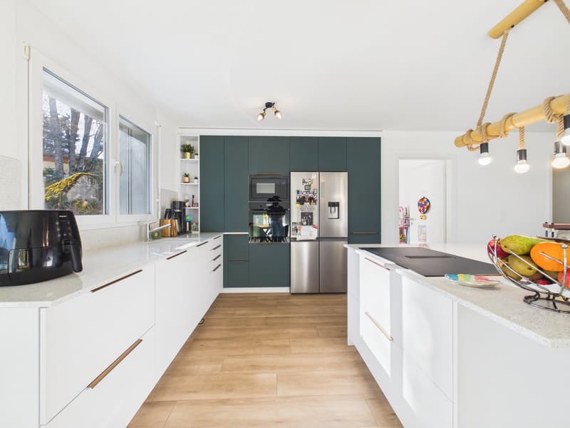 modern kitchen with white cabinets, wooden floor, green cabinets, stainless steel appliances, large window