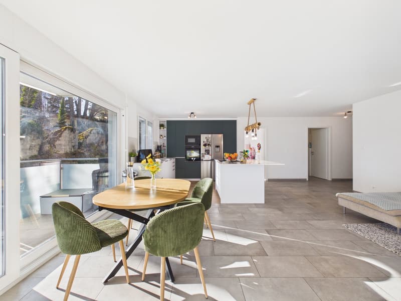 Dining room: open layout with kitchen, large window, wooden dining table, green chairs, glass door, balcony, tiled floor, stainless steel refrigerator, kitchen counter