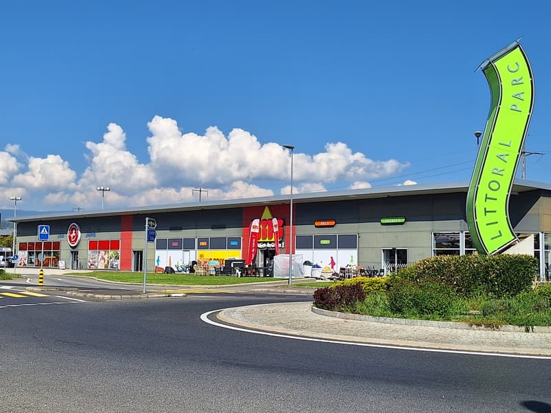A large retail store with a red and black exterior, a green and white 'Little Park' sign, and a parking lot in the foreground.