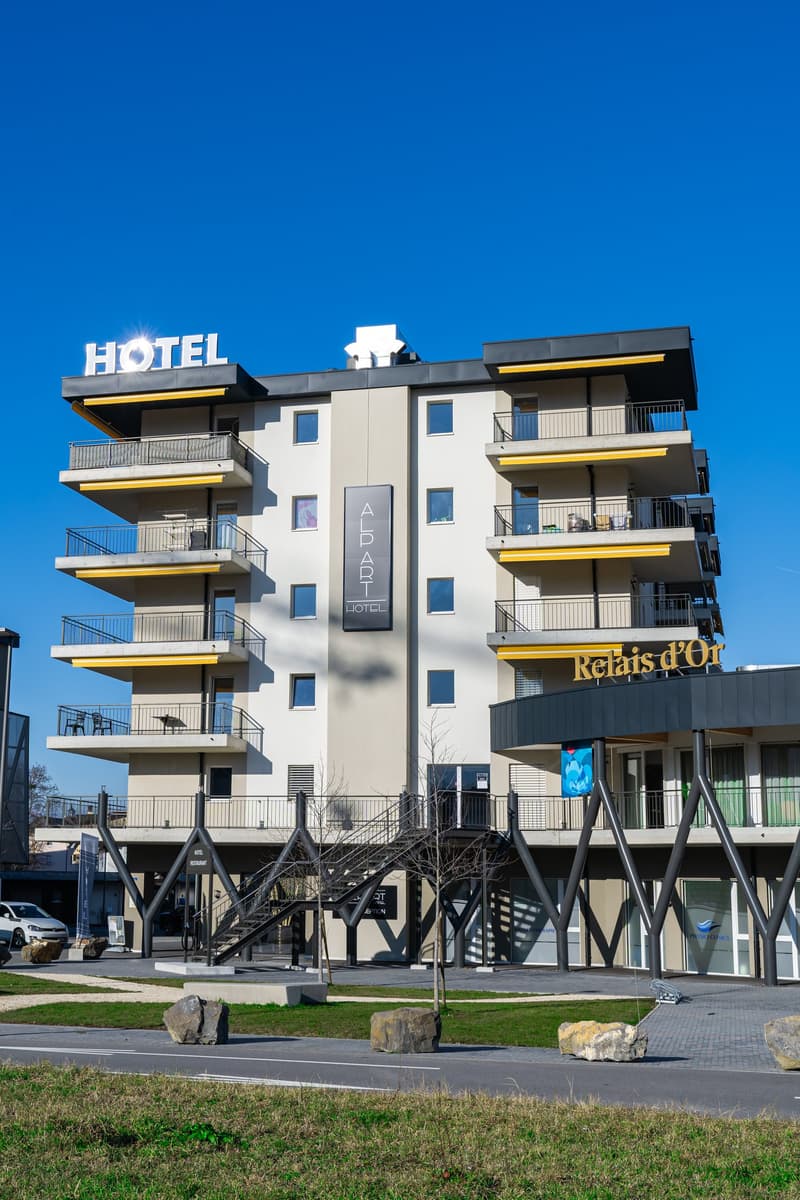 Hotel building with balconies, large windows, staircase, and entrance