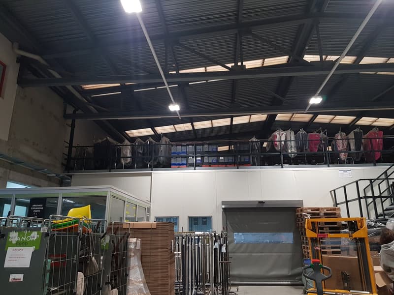 large warehouse, metal ceiling, metal railings, storage boxes, roll-up door, metal shelves, metal racks