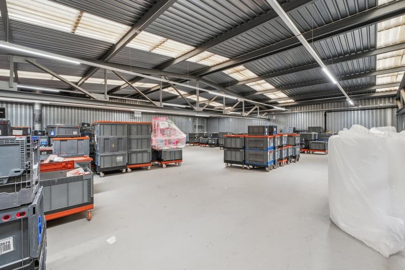 large warehouse, metal walls, metal ceiling, fluorescent lighting, multiple storage boxes, plastic bags