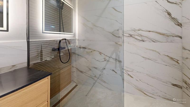 Contemporary bathroom with walk-in shower, marble tiles, vanity with a wooden cabinet, mirror with lighting