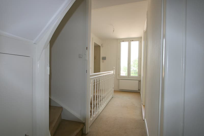 Entranceway with carpeted floor, wooden handrail, radiator