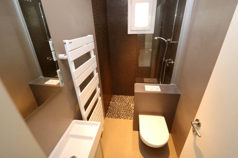 small bathroom with shower, toilet, sink, and towel rack
