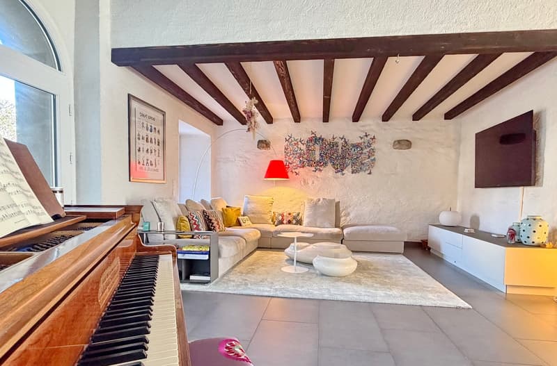 wooden beams, white walls, large couch, piano, round coffee table, side table, art piece, large window, decorative items