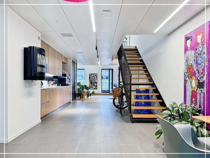 long hallway, tiled floor, wooden cabinets, hanging black object, staircase with bicycle, potted plants, painting on wall