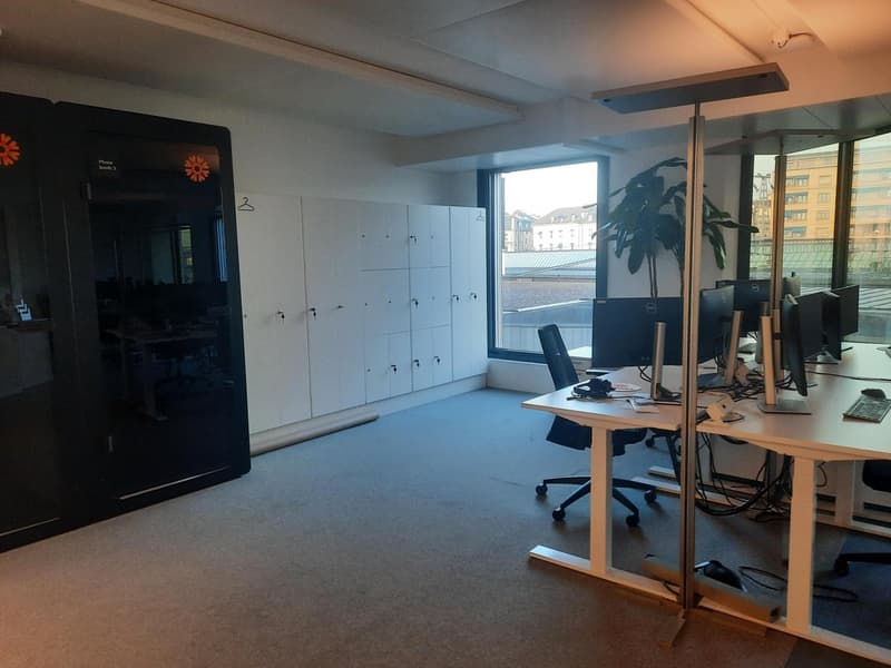Open office space with desks, chairs, storage cabinets, office equipment and view of the city