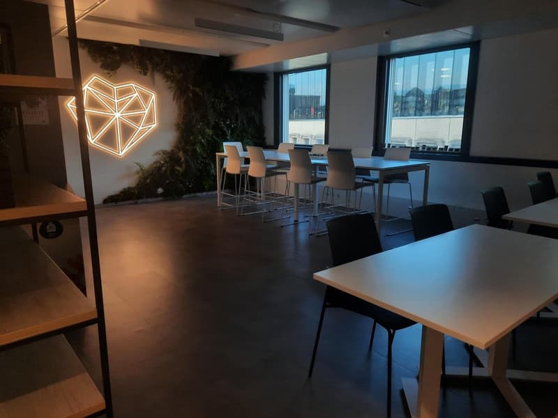 modern meeting room with white tables and black chairs, LED lit green plant wall, heart design wall decoration, large windows