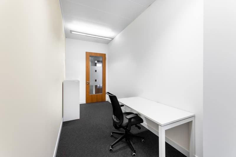 empty room, white walls, white desk, black chair, wooden door