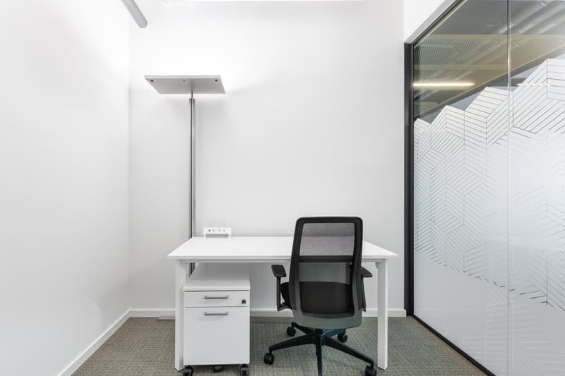white desk, black office chair, white drawers, white walls, glass wall with pattern