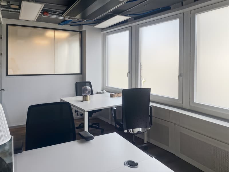 modern office room with white walls, white desks, black chairs, large windows, ceiling lamps
