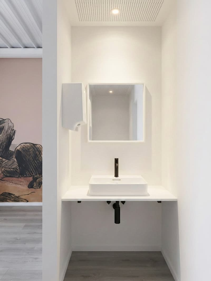White sink, white countertop, mirror, artwork, dispenser, tiled floor