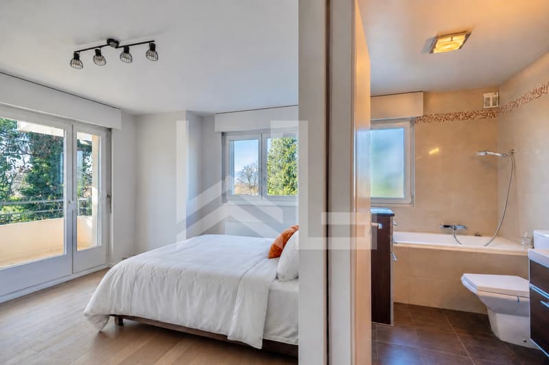 Corsier / a modern bedroom with a white bed and large window overlooking the bathroom