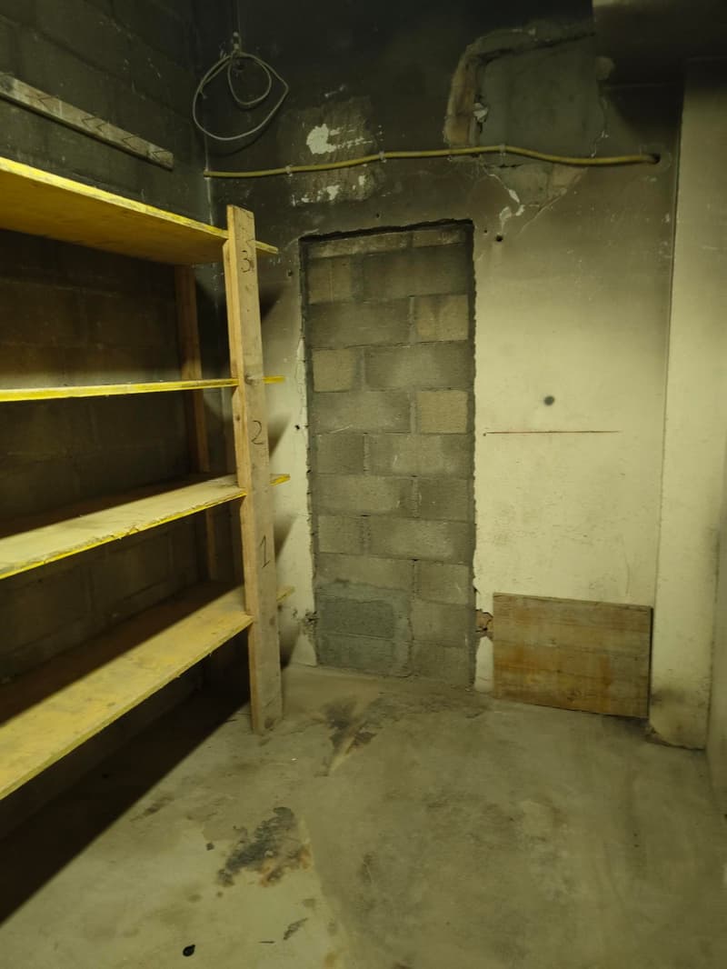 Empty room with brick wall, wooden shelves, and a hole in the wall