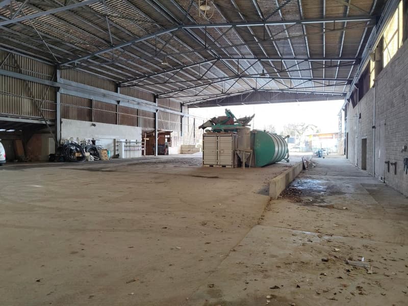large warehouse with metallic ceiling, wide open space, machinery, containers