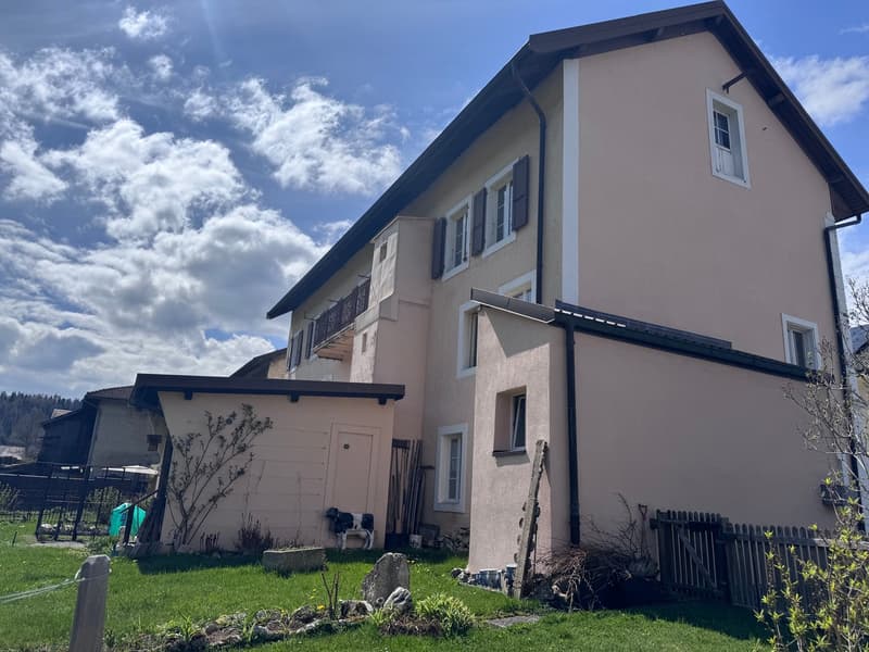 2 story house, beige exterior, black roof, balcony, garage, garden, cow statue