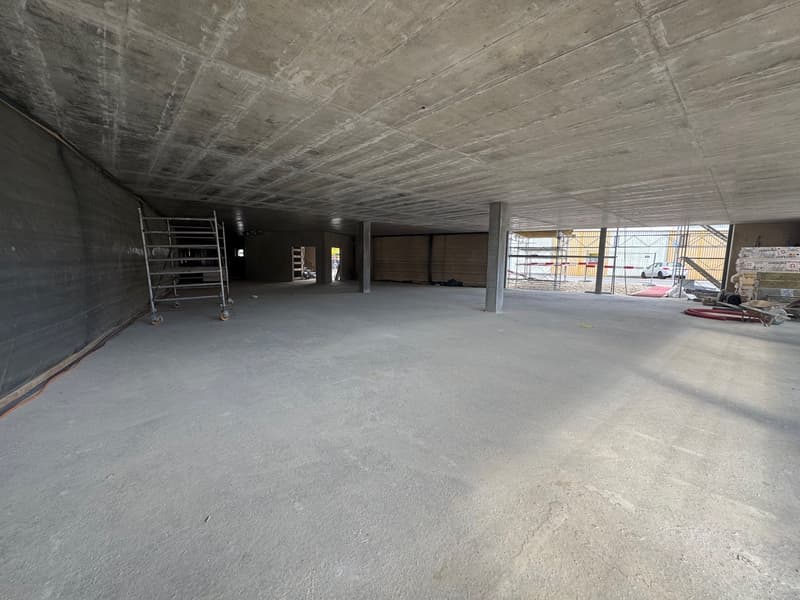 Empty room with concrete floor, walls, and ceiling, metal scaffolding, and construction materials