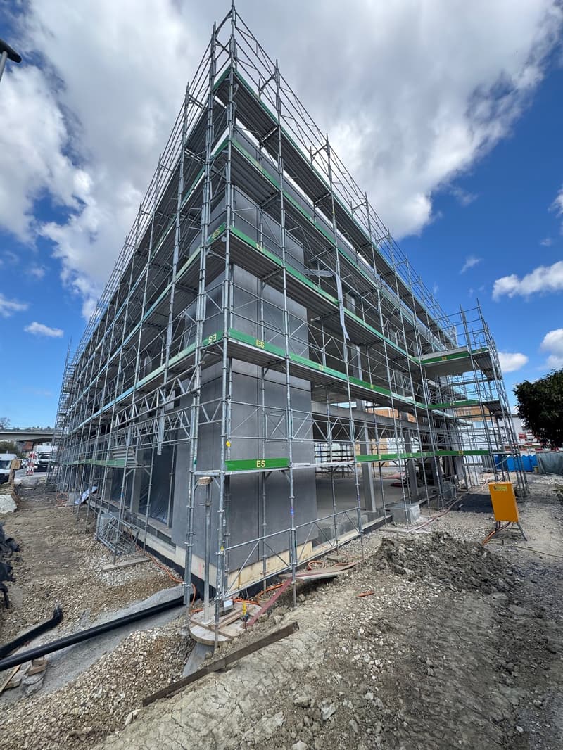Building under construction, metal scaffolding, concrete foundation, multiple floors, construction site
