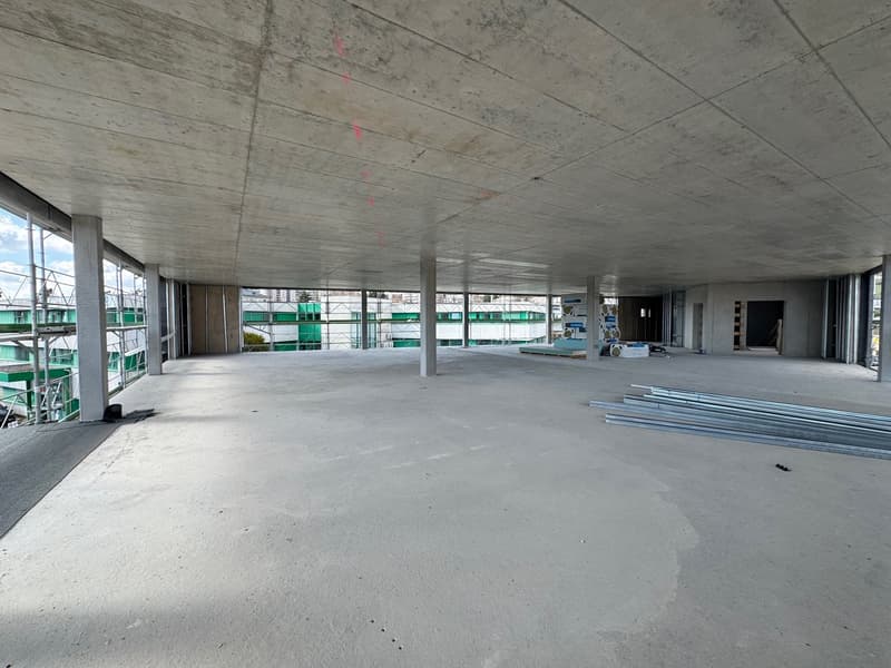 Empty room with concrete floor, metal beams, and large windows