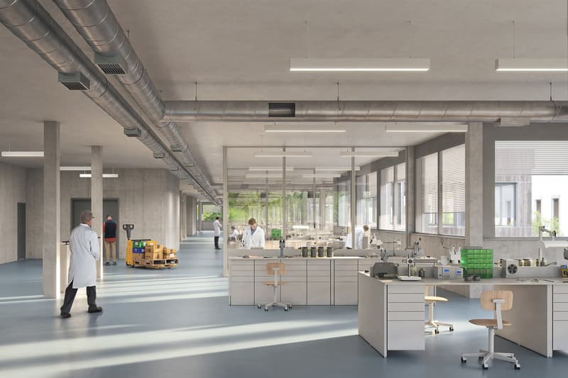 Industrial building with labs, concrete walls, overhead pipes, long hallway, large windows, work tables, carts, office chairs