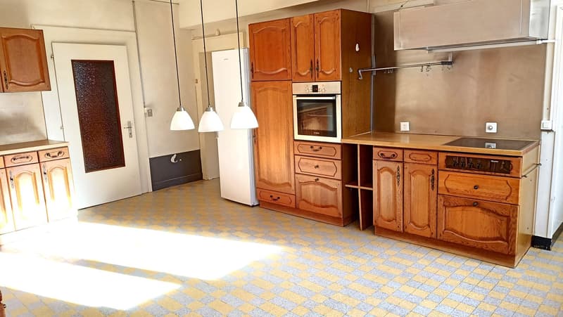 Spacious kitchen with wooden cabinets, built-in oven, dishwasher, and tiled flooring