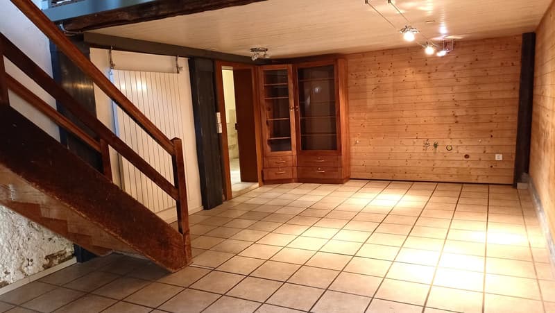 Spacious room with wooden walls and ceiling, tiled floor, built-in shelves and cabinets, and a staircase leading to another level.