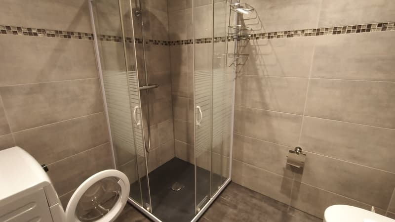 tiled walls, tiled floor, glass shower stall, toilet, washing machine