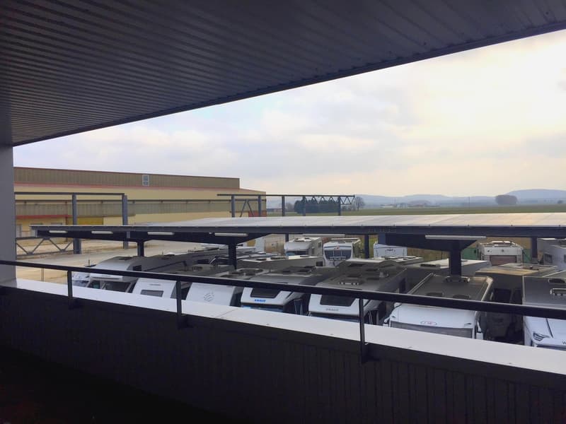 covered parking lot with solar panels, multiple white vehicles parked