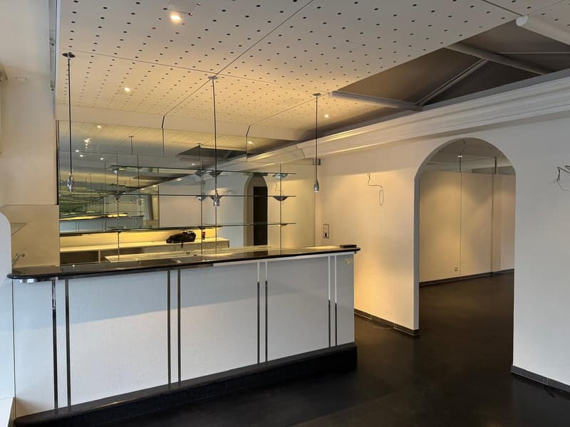 Modern interior with minimalist design, arched walls, a mirrored ceiling, large reception desk, sleek metallic accents, and contemporary lighting fixtures.