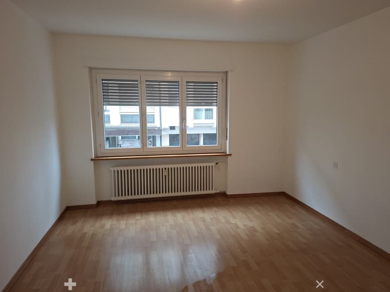 empty room with a window, white walls, wooden floor, radiator