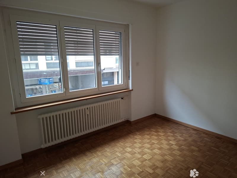 Empty room with wooden floor, white radiators, white walls, windows, exterior view