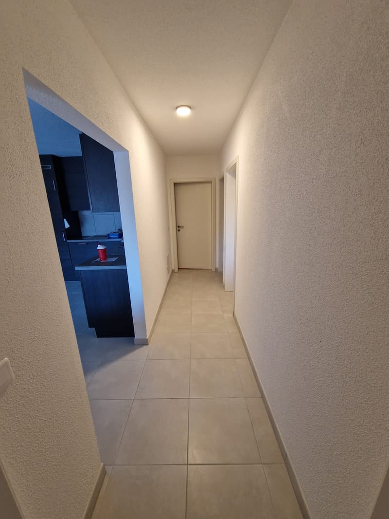 Empty hallway with tiled floor, white walls, and a ceiling light