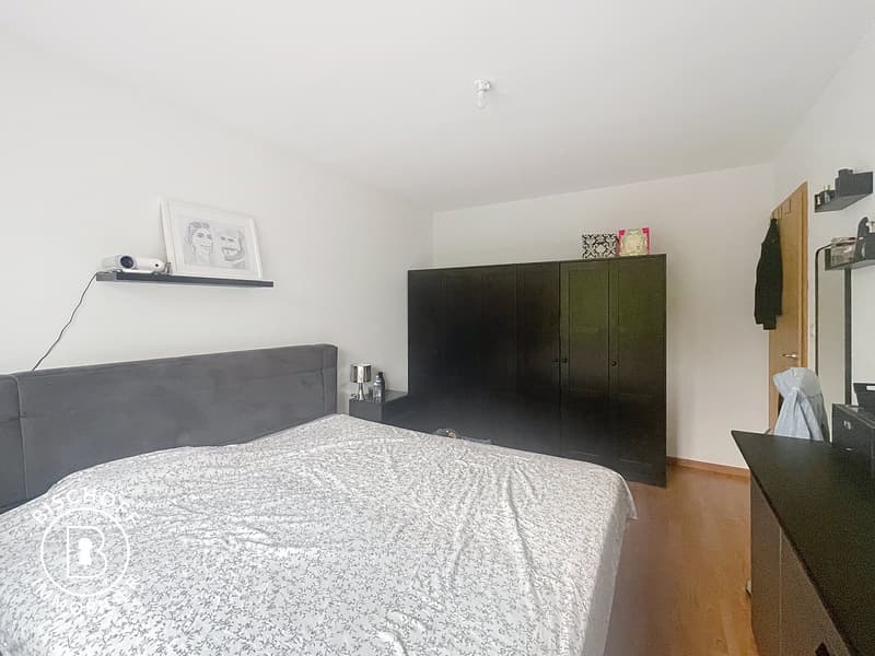 large bed, wooden floor, dark gray headboard, wooden shelves, wardrobe, lamps