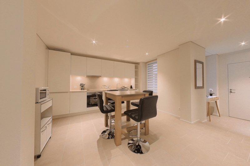 Wooden kitchen table, 4 black chairs, cabinets with countertops, appliances, light fixtures, beige floor