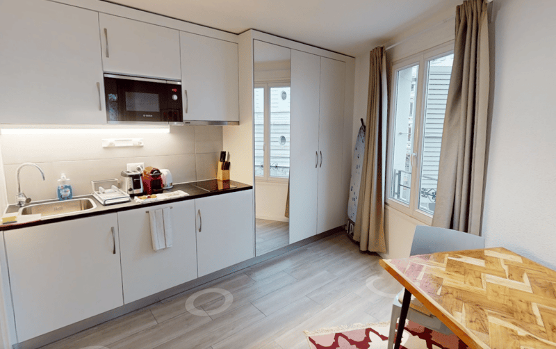white cabinets, wooden floor, sink, microwave, kettle, toaster, small dining table