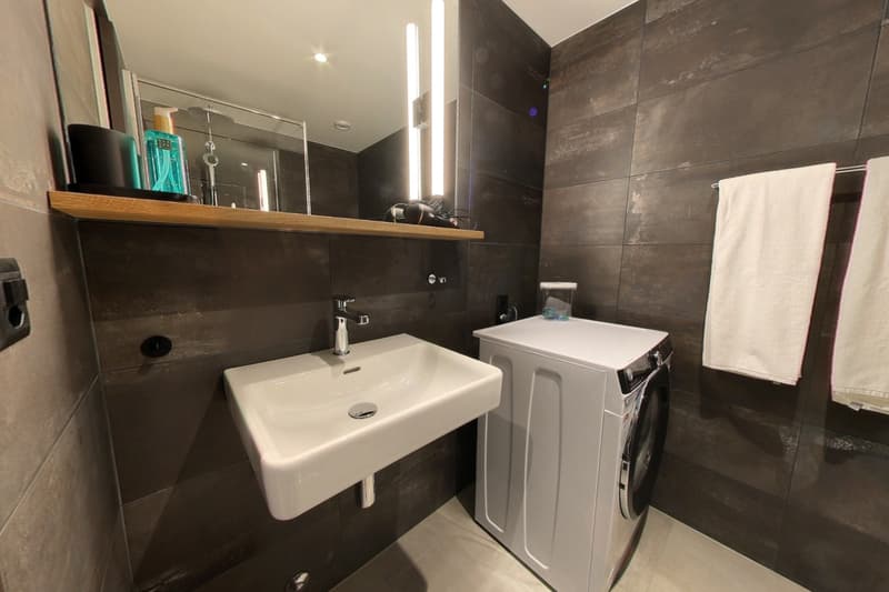 modern bathroom with tiled wall, white sink, modern faucet, washing machine, full length mirror