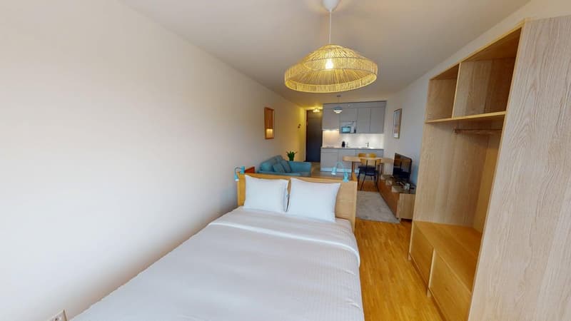 Small bedroom with bed, couch, tv and kitchen area