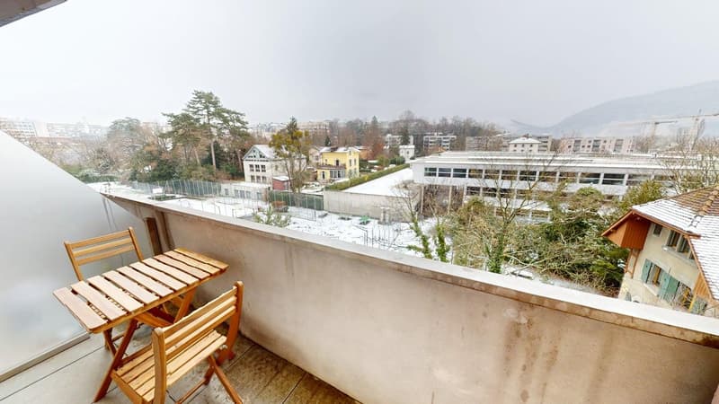 Balcony with table and chairs, glass railing, view of snowy landscape