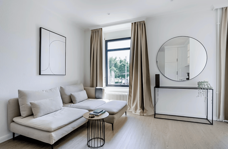 large sofa, console table, round mirror, white walls, wooden floor, white curtains