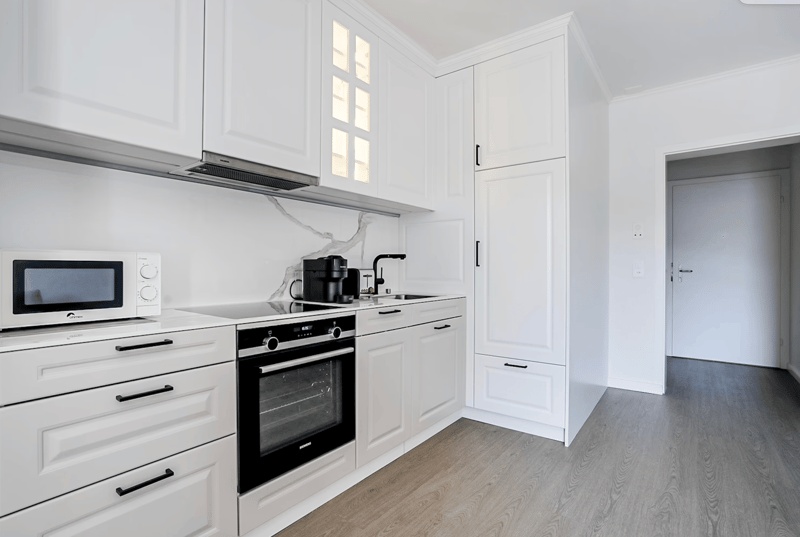 modern kitchen with granite countertop, white cabinetry, stainless steel appliances, wooden floor, sink, faucet, coffee machine, microwave, oven, dishwasher
