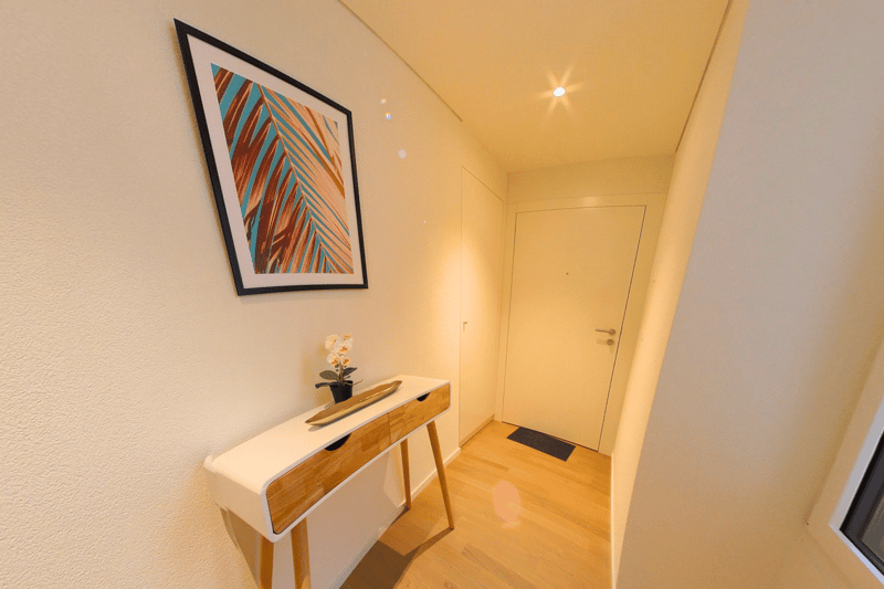 White walls, wooden floor, modern white table with drawers, picture frame, white door, window