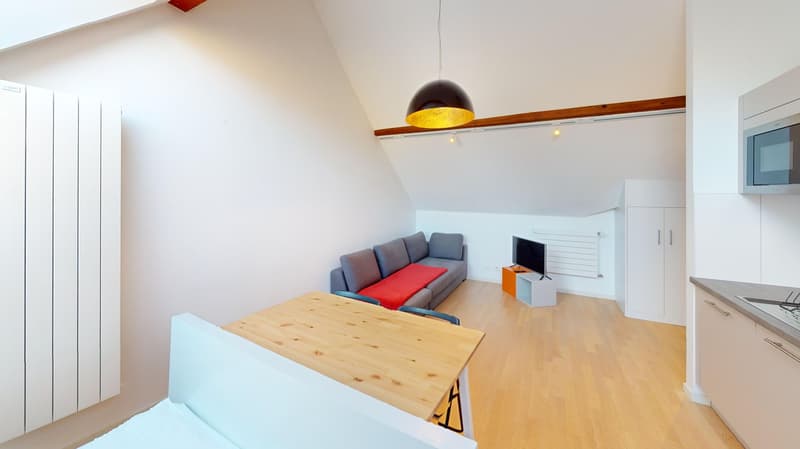 Open floor plan, gray couch, orange table, television, wooden floors
